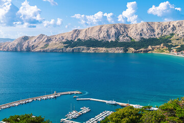Sunny day at scenic coastal harbor with boats and mountain views. Ba&scaron;ka, Krk island, Croatia