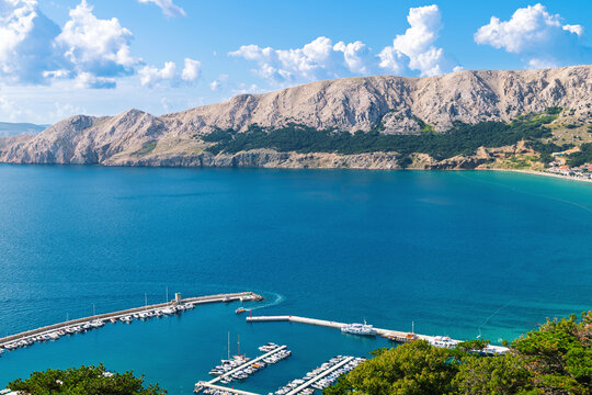 Sunny day at scenic coastal harbor with boats and mountain views. Baška, Krk island, Croatia