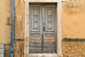Rustic wooden door with weathered paint and stone frame on aged wall