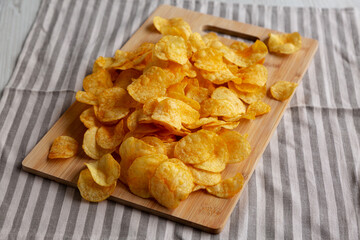 Crunchy Meat Frying Pan with Mushrooms Chips on a Wooden Board, side view.