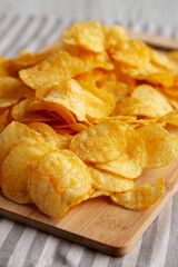Crunchy Meat Frying Pan with Mushrooms Chips on a Wooden Board, side view.