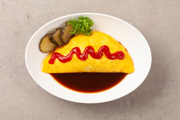 밥을 고기나 야채 따위와 함께 볶고 그 위에 달걀을 얇게 부쳐서 씌운 요리.
A dish made by stir-frying rice with meat or vegetables and topping it with a thin layer of fried egg.

