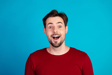 Young handsome man in red shirt smiles with surprise against blue background for advertising lifestyle fashion and shopping campaigns