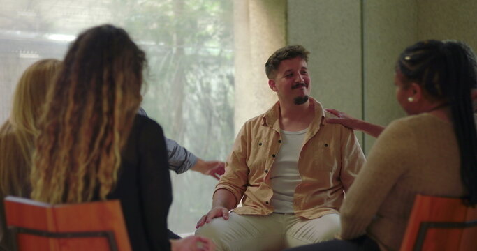 Man overwhelmed with emotion in group therapy, sitting with head in hand during intense moment of breakdown and emotional release among supportive peers