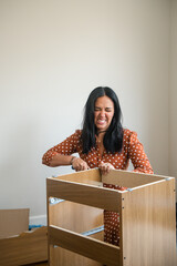 A woman is working on a wooden box, and she is wearing a polka dot dress