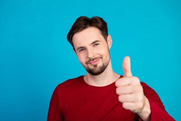 Young handsome man with red sweater gives thumbs up against blue background for lifestyle...