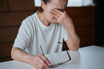 メガネを持ちながら目を押さえるシニア女性