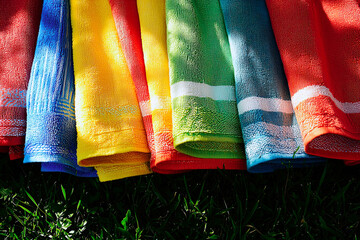 AI Generated - Row of colorful towels sitting on top of a lush green field. Professional stock photography. Stock photo. High-resolution. High-res. Premium quality. Premium. Professional grade.