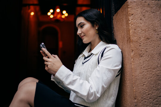 Close-up of teen woman with phone, scrolling attentively with focused expression, representing daily smartphone routines and mobile communication habits.