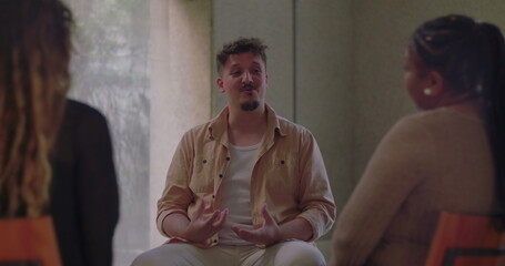 Man speaking from the heart in therapy group, using expressive gestures to share personal story while surrounded by attentive and supportive participants