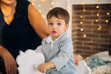 Child riding on rocking horse while being watched by adult in a cozy, decorated indoor space with fairy lights, creating a warm atmosphere in the evening