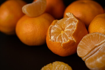 Fresh mandarines, peeled and whole with on minimalistic dark background. Top view.