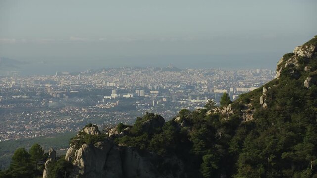 Vue de Marseille depuis le massif de l&rsquo;&Eacute;toile, vue a&eacute;rienne en mouvement avec les arbres et la roche au premier plan 