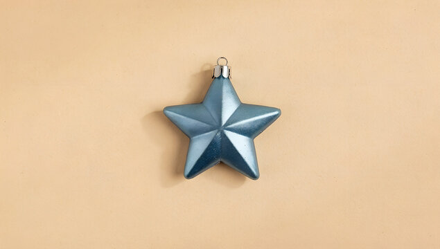 Blue holiday star decoration on soft beige background. Minimal concept idea
