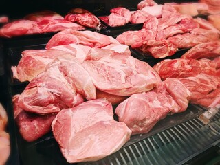 Fresh Raw Pork Cuts in Butcher Shop Display. Assorted chilled pork cuts including chops, ribs and shoulder neatly arranged on black trays in butcher shop counter. Meat and food concept.