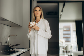 Woman enjoying morning coffee in kitchen pajamas