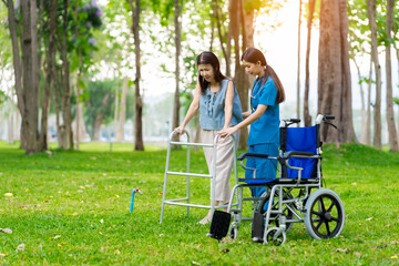 A female doctor helps an elderly Asian woman, giving her encouragement and relaxation in the green nature, helping her learn to walk with a cane.