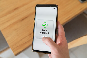 Loan approved notification on smartphone screen. Concept of debt and mortgage.