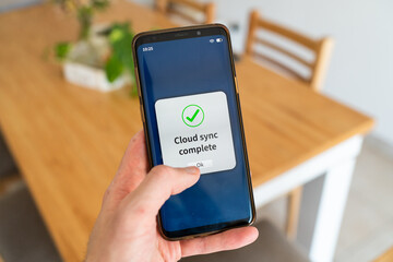 Cloud sync complete message on smartphone. Concept of syncing data on the cloud.
