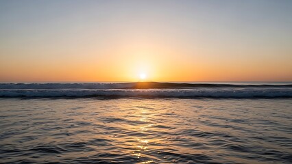 Fototapeta premium Calm ocean water with a bright sunset and sun reflecting on the surface waves