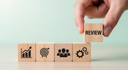 Business performance review concept hand placing a block with the word review on top of blocks with business icons