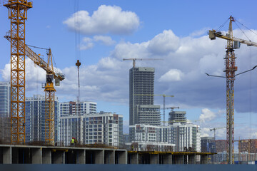 Fototapeta premium Construction cranes and new buildings, construction work of modern skyscrapers on a sunny day.