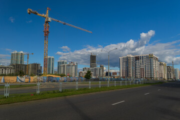 Construction of buildings and high-rise cranes against the sky and city street © Tatiana