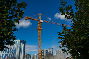 Construction of buildings and high-rise cranes against the sky and city street © Tatiana