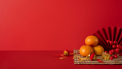 Side view of a festive Chinese New Year arrangement using oranges, gold ingots, beads and a woven mat with red lanterns creating a warm, prosperous greeting for the new year