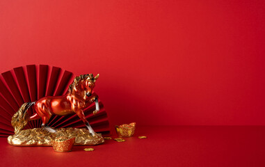 Side view of a glossy golden horse statue beside coins and gold ingots against a red backdrop, symbolizing prosperity. A festive Chinese New Year greeting and fortune theme for celebrations