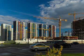Construction of buildings and high-rise cranes against the sky and city street © Tatiana