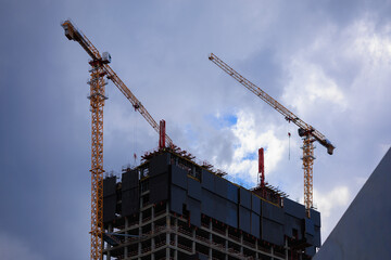 Construction of buildings and high-rise cranes against the sky and city street © Tatiana