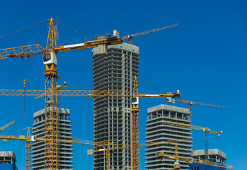 Construction of buildings and high-rise cranes against the sky and city street © Tatiana