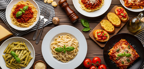 Hearty Italian favorites such as spaghetti, penne pesto, fettuccine alfredo and baked lasagna are arranged in a cozy tabletop spread that showcases rich sauces and fresh ingredients.