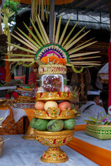Traditional Balinese Hindu offering Gebogan. Tall tower of fresh tropical fruits, cakes and flowers on golden stand. Ritual sacrifice ceremony in temple during Galungan festival in Bali, Indonesia.