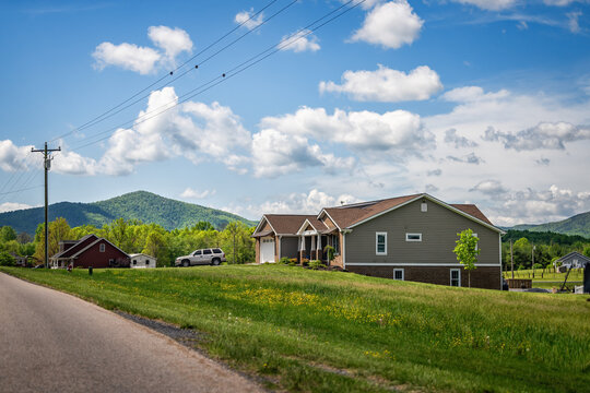 Countryside rural paved road leading to Lyndhurst, Virginia in summer season with houses and lush mountains
