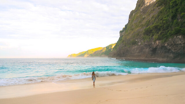 Woman Relaxing On Remote Kelingking Beach Bali With Turquoise Sea And Cliffs