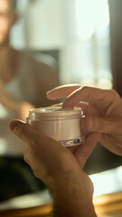 Male hands opening facial cream in soft daylight. Concept of skincare brands, packaging design, educational materials, product texture clarity, simple men routines.