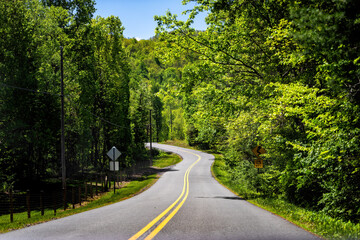 Rural paved winding road in Lyndhurst, Virginia summer countryside season with lush trees forest woods and sign