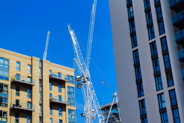 Tower cranes at a high-rise construction site, showcasing the large industrial machinery essential for lifting and moving heavy materials. © Somkiat
