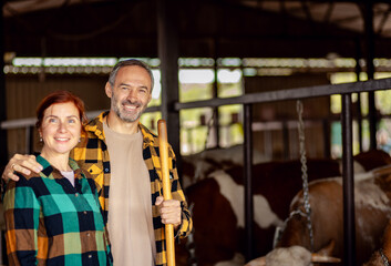 Portrait of female and male farmer in cow farm looking at camera.