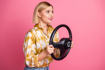Young female model wear blouse holds steering wheel pink studio background casual fashion style...