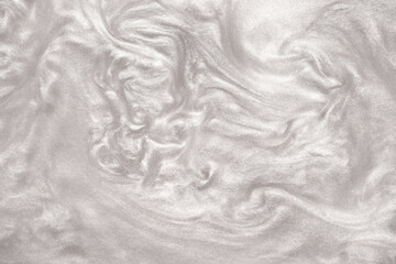 Shimmering silver abstract background. Liquid glitter paint texture waves and swirls. Beautiful shiny white glitter texture. Metallic silver paint close-up as a holiday background.
