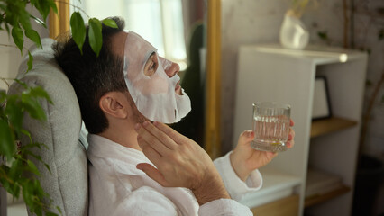 Man sitting with face mask and glass of water in peaceful moment. Concept of wellness media,...