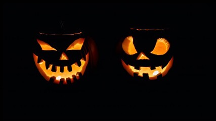 Halloween holiday promotion theme. Spooky scaring. A closeup shot of two carved pumpkins set against a dark background. The pumpkins are illuminated from within, casting a warm.