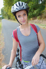 young female cyclist riding her bicycle with safety helmet