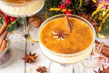 Traditional Christmas Eggnog Martini Or Brandy Alexander Cocktail with cinnamon and nutmeg, with golden Christmas decorations and bokeh effect, copy space