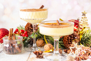 Traditional Christmas Eggnog Martini Or Brandy Alexander Cocktail with cinnamon and nutmeg, with golden Christmas decorations and bokeh effect, copy space