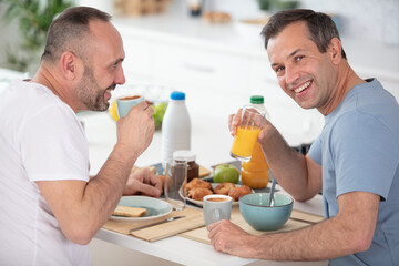 gay couple have breakfast in the kitchen in sunny day