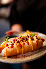 A gourmet hot dog loaded with chili, mustard, and ketchup, topped with sprinkles and a parsley...